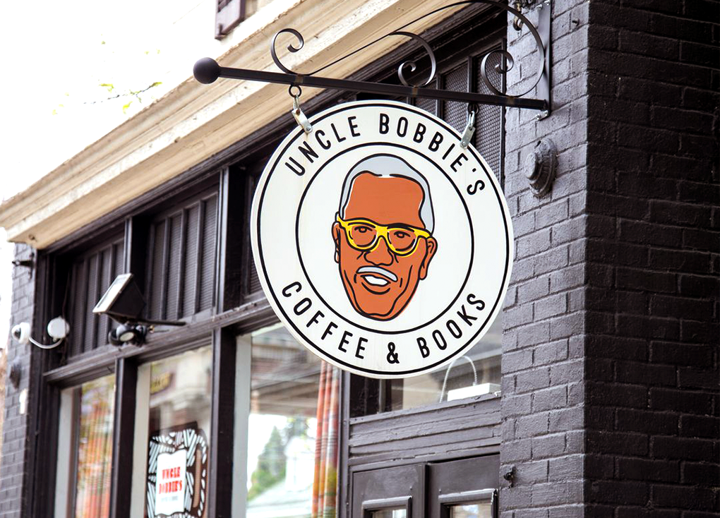 a brick building painted black with a circular hanging sign for Uncle Bobbie's Coffee and Tea