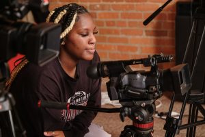 young Black woman operating a video camcorder